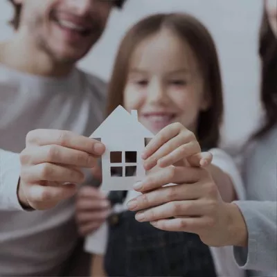 Famille avec projet immobilier tenant une façade de maison en papier